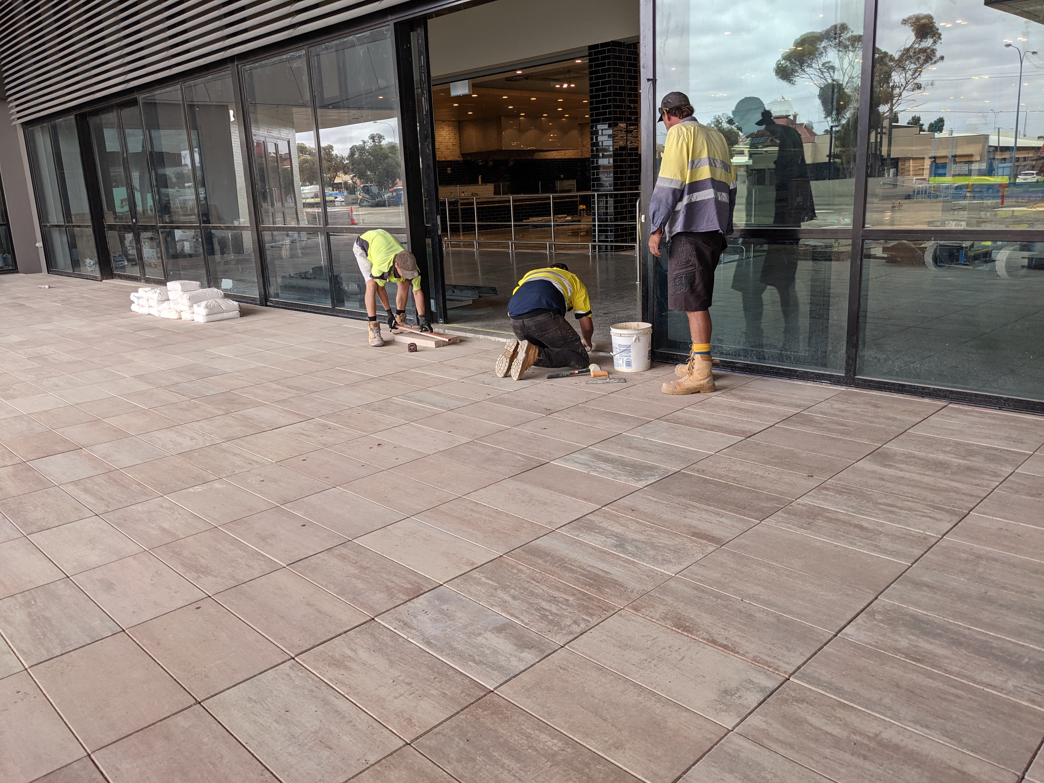 Phoenix Goldfields workers laying tiles on commercial building forecourt in Kalgoorlie