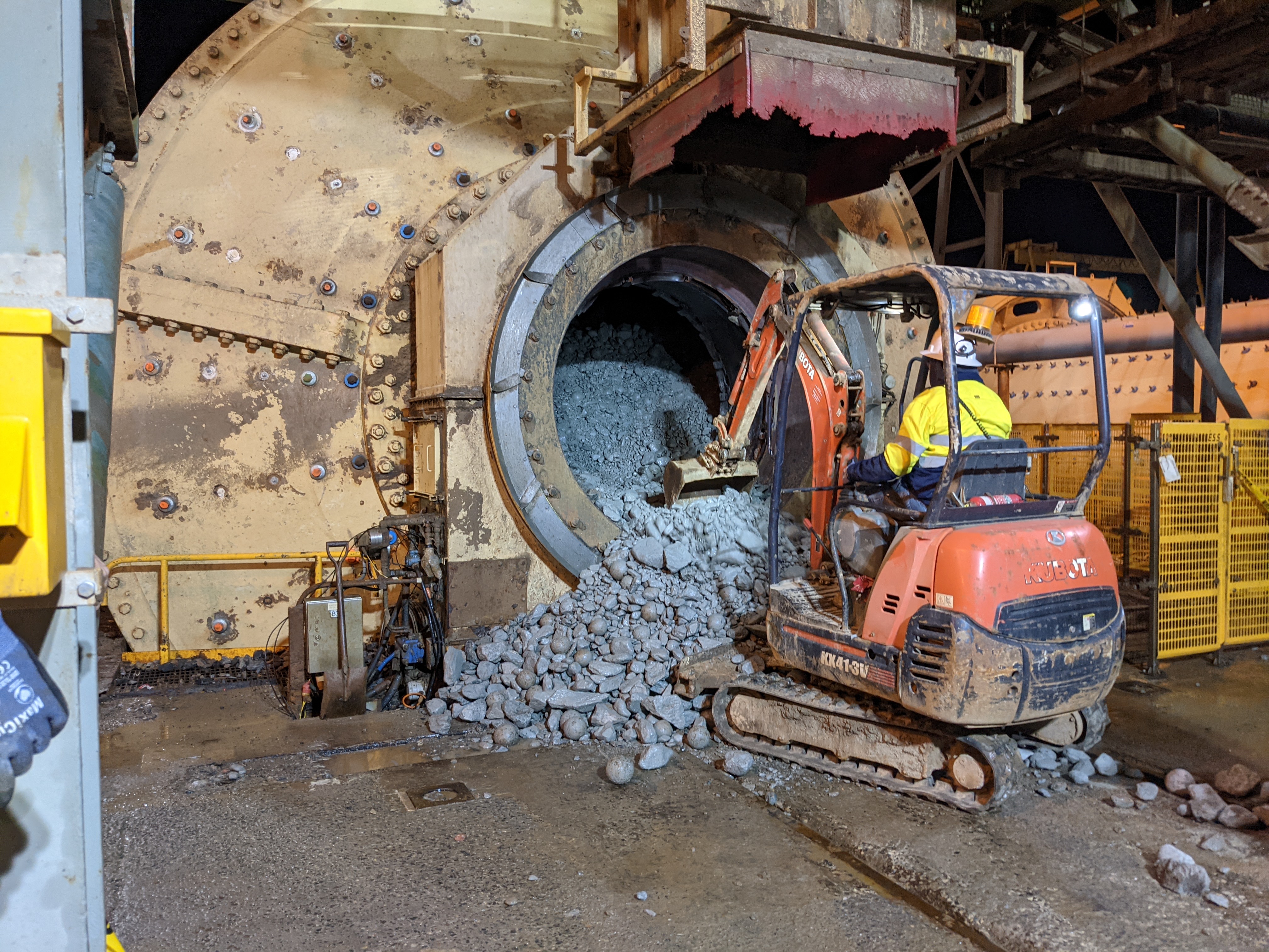 Mini excavator cleaning out ball mill during major mine site shutdown by Phoenix Goldfields